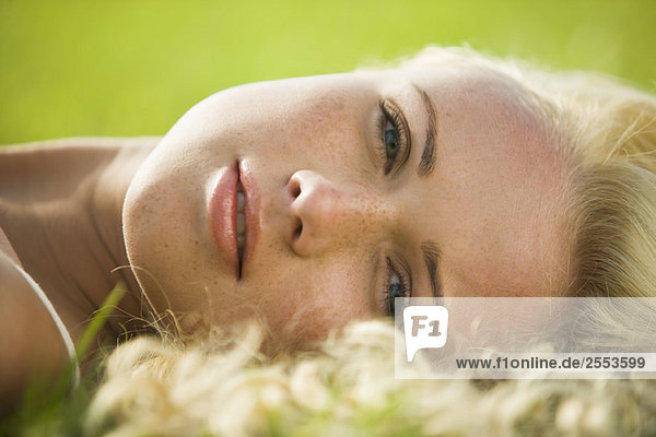Porträt einer jungen Frau im Gras liegend