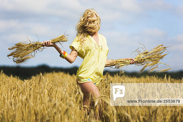 Junge Frau mit Weizen auf dem Feld