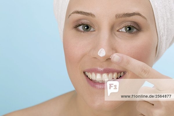Frau tupft Gesichtscreme auf ihre Nase