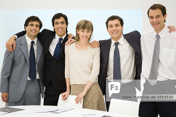 Business team standing with arms around each other's shoulders  smiling at camera