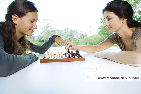 Zwei Frauen spielen Schach  eine macht einen Zug  die andere berührt ihre Hand.
