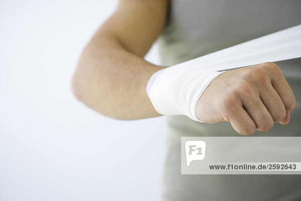 Man wrapping bandage around wrist  cropped view