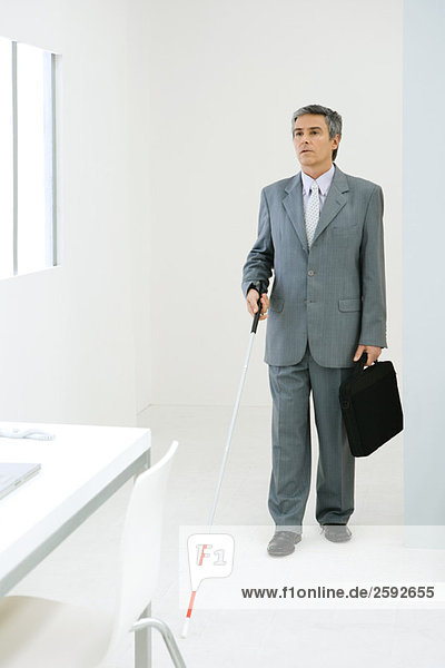 Blind businessman entering office  using white cane