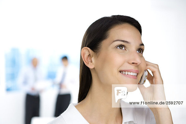 Professional woman using cell phone  looking up  smiling