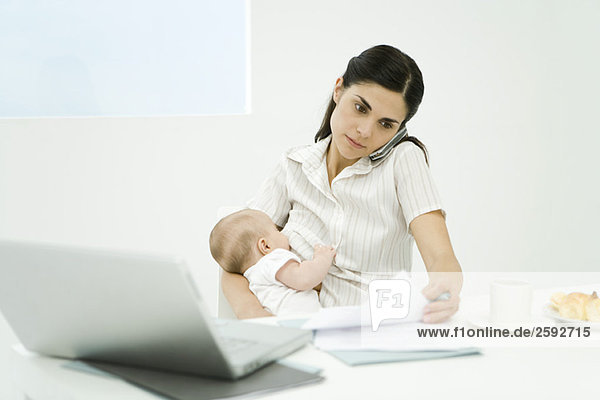 Professional woman using cell phone  holding baby  looking at document