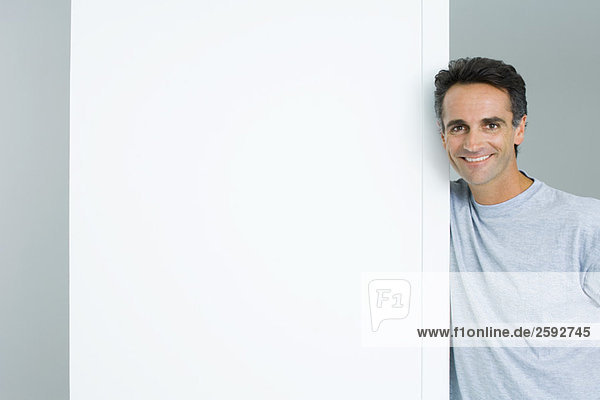 Mann lehnt sich gegen die Tür und lächelt in die Kamera.