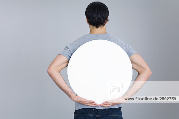 Mann hält leeres Rundschild hinter dem Rücken  Rückansicht