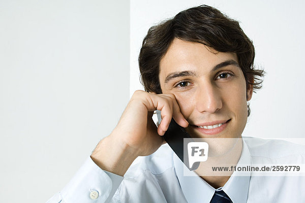Young man using cell phone  smiling at camera