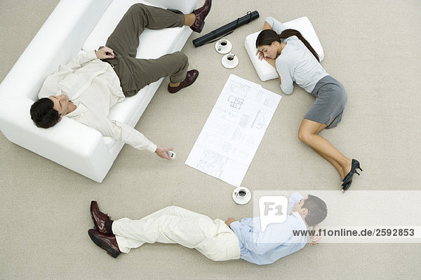 Team von Profis  die auf dem Boden und Sofa schlafen  Blaupause auf dem Boden zwischen ihnen  Blick nach oben