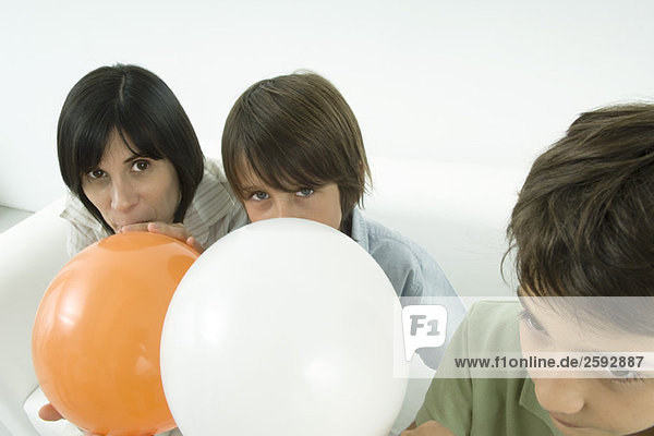 Mutter und Söhne beim Aufblasen von Luftballons