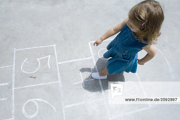 Kleines Mädchen spielt Hopscotch im Freien  Draufsicht