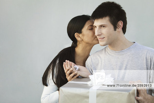 Couple exchanging gifts  woman kissing man on cheek