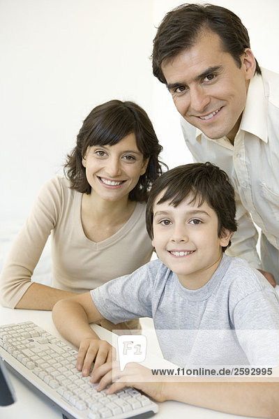 Boy with parents  using keyboard  all smiling at camera
