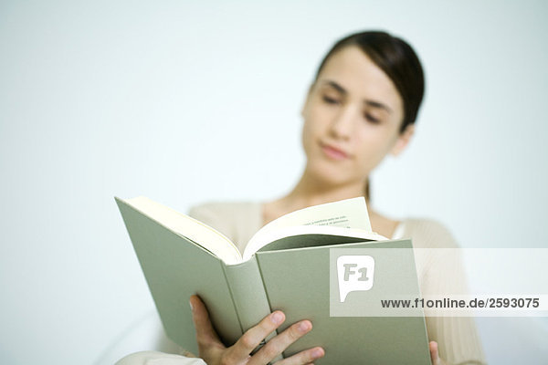 Young woman reading  focus on book in foreground