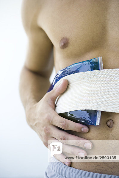 Man holding cold compress against abdomen  cropped view