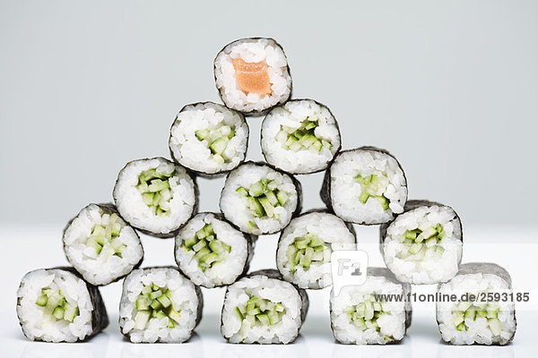 Gruppe von Maki-Sushi in Form einer Pyramide mit einem Stück Lachs-Maki-Sushi an der Spitze angeordnet