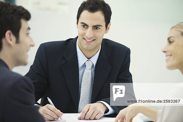 Business associates having discussion  smiling at each other  man taking notes