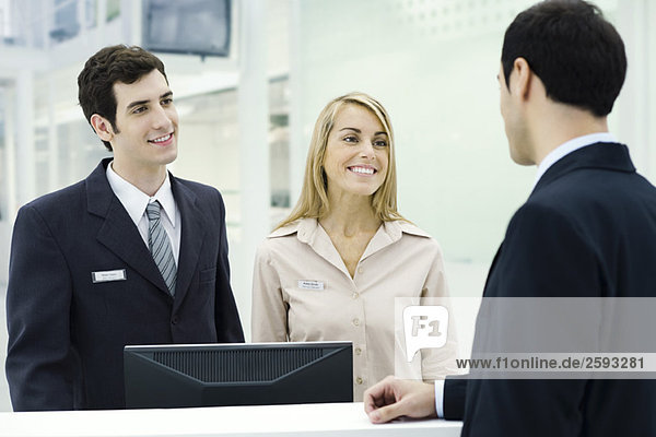 Customer service representatives smiling at businessman waiting at counter