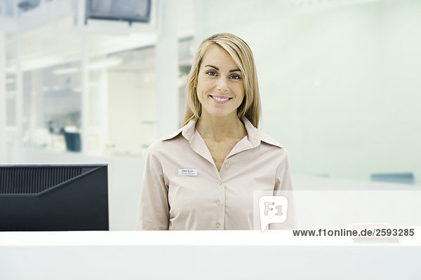 Well dressed woman standing behind counter  smiling at camera  portrait
