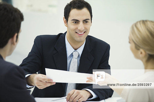 Meeting between professional and clients  man passing document to woman