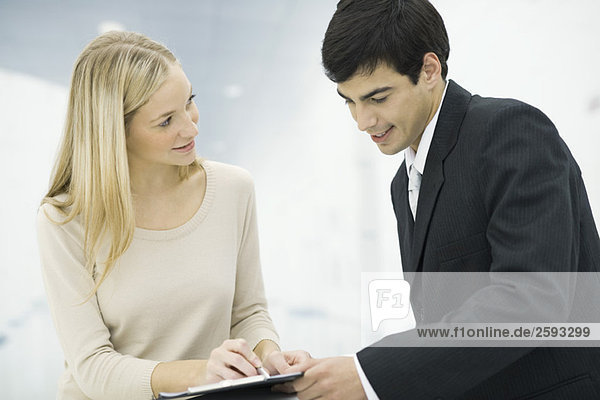 Woman holding clipboard showing document to associate