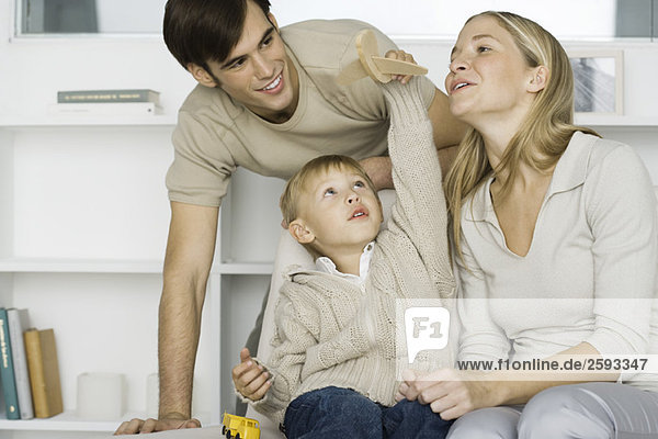 Little boy playing with toy airplane  parents watching