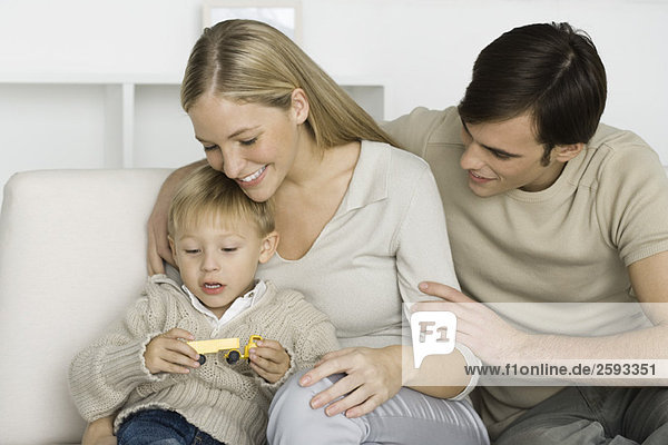 Parents and young son looking at toy truck  smiling