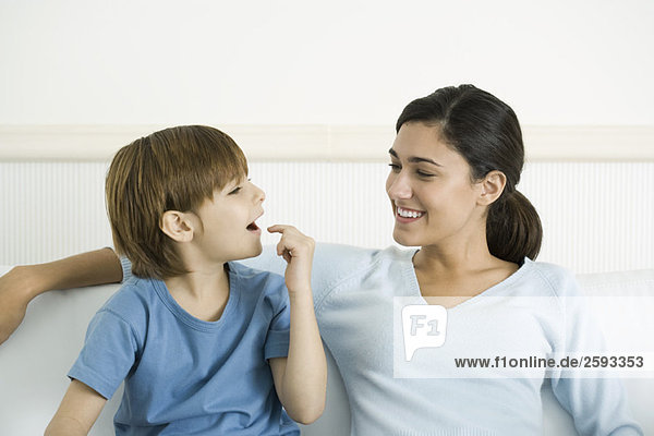 Mother and son sitting together  boy pointing to open mouth