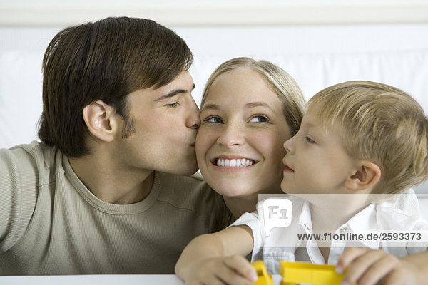 Man kissing wife on the cheek  young son watching