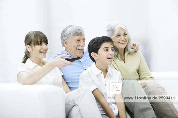 Mehrgenerationen-Familie  die zusammen auf dem Sofa sitzt und fernsieht.
