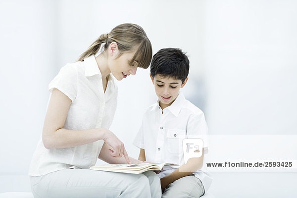 Young woman and boy reading book together