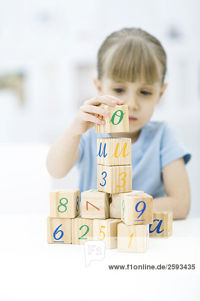 Little girl stacking blocks  focus on foreground