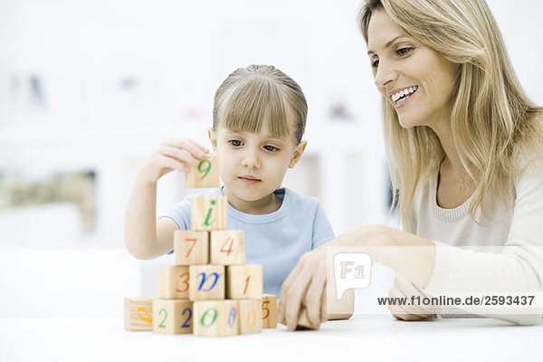 Little girl stacking blocks  mother watching and smiling