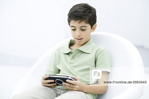 Junge spielt Handheld-Videospiel