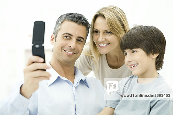 Familie schaut gemeinsam auf das Handy  lächelnd