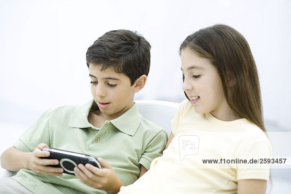 Bruder und Schwester sitzen zusammen  Junge spielt Handheld-Videospiel