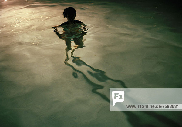 Eine junge Frau steht nachts im Schwimmbad  Silhouette