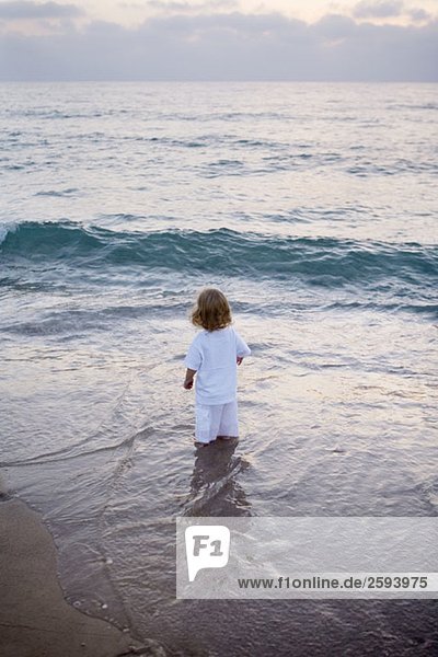 A child standing in the surf on a beach