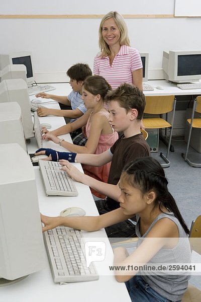 Ein Lehrer und vier Kinder vor der Pubertät in einem Computerlabor