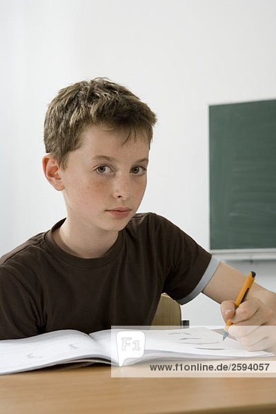 A pre-adolescent boy studying in a classroom