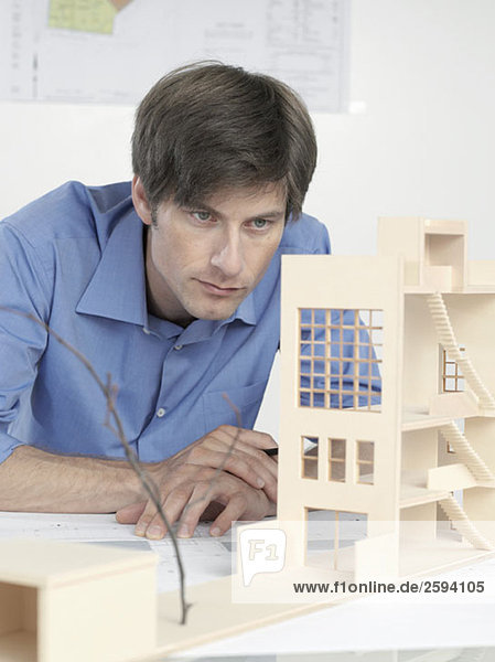 Ein Architekt  der ein Architekturmodell untersucht.