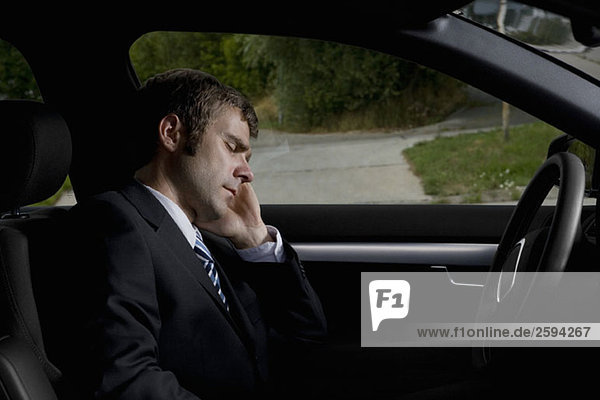 A businessman sleeping in a car