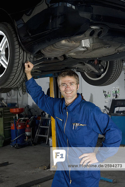 A car mechanic standing underneath a car