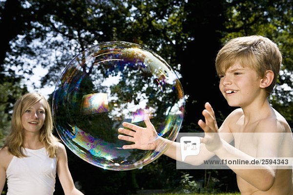 Zwei Kinder versuchen  eine Blase zu fangen.