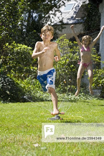 Two children playing in a sprinkler