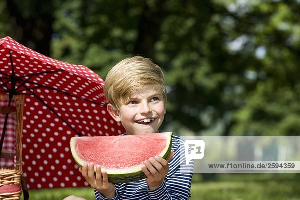 Ein kleiner Junge hält eine Scheibe Wassermelone.