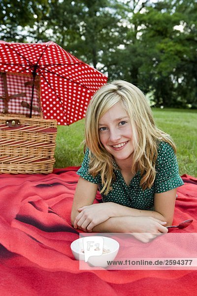 Ein Mädchen mit einer Schale Joghurt  Müsli & Erdbeeren beim Picknick