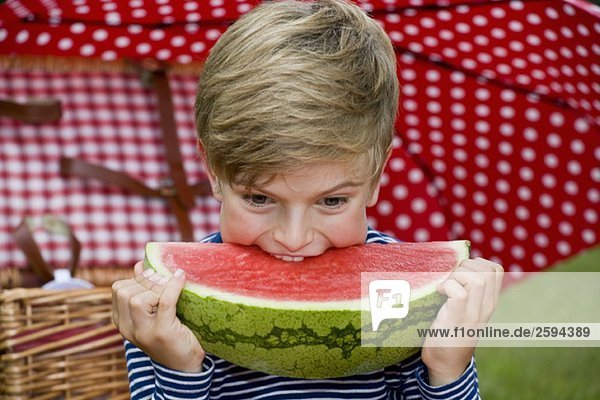 Ein kleiner Junge  der eine Scheibe Wassermelone isst.