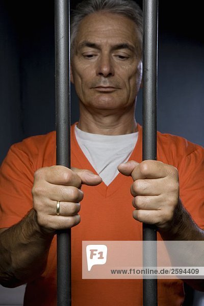 Ein Gefangener  der hinter Gittern steht.
