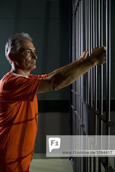 Ein Gefangener  der in seiner Zelle steht.